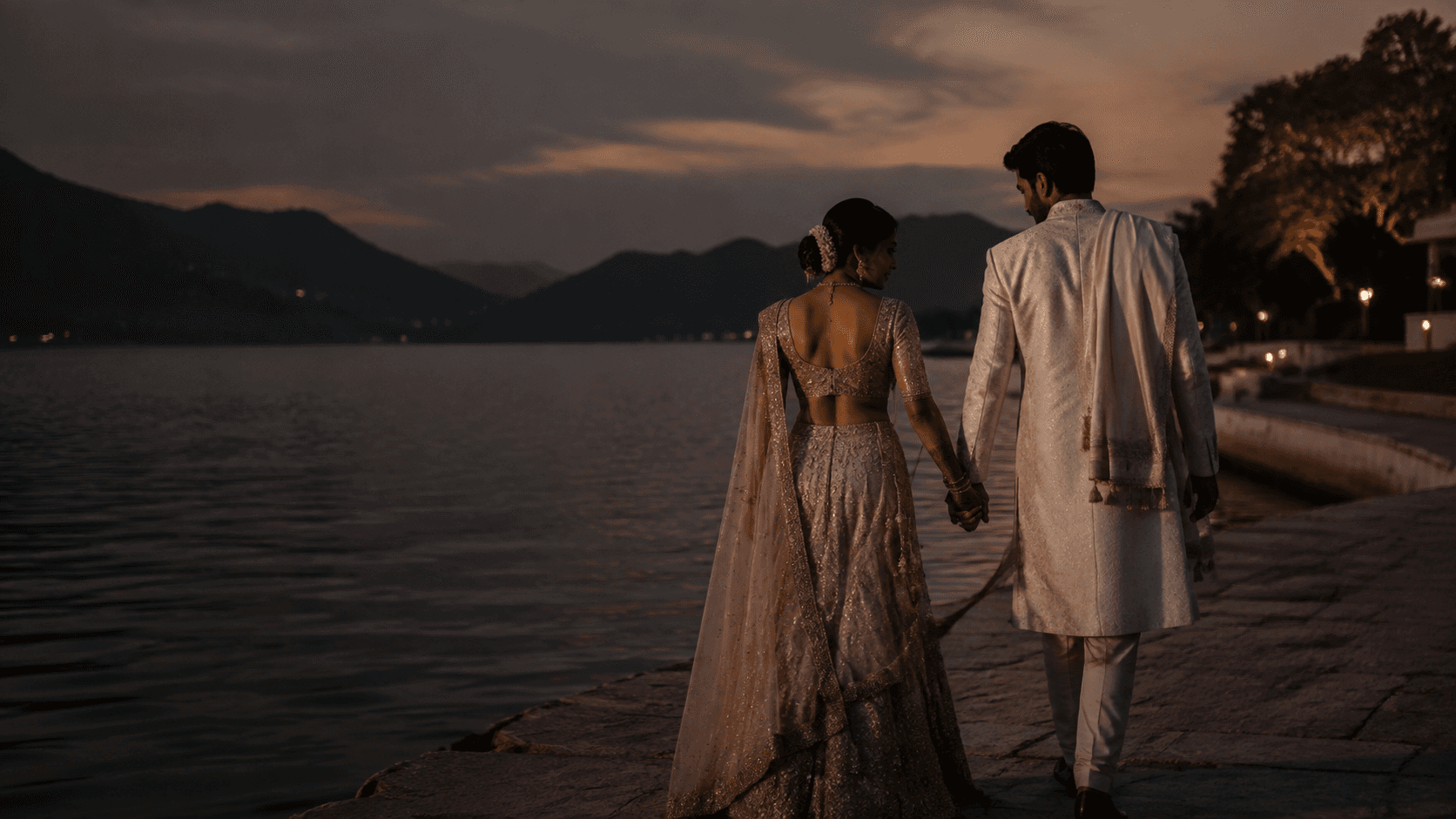 Newlyweds walking together beside a lake at dusk